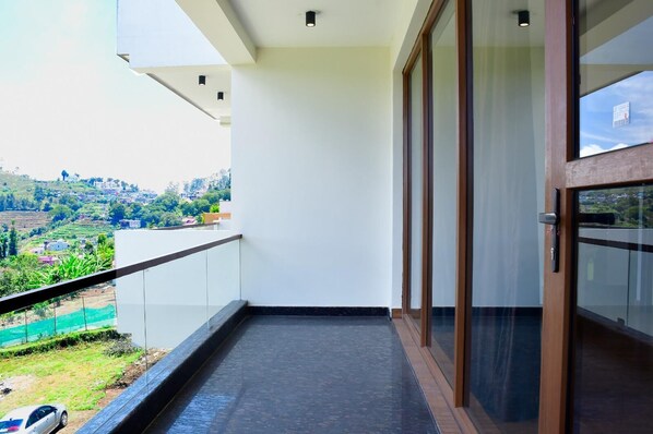 Un balcon donnant sur un paysage verdoyant et sur des bâtiments situés au loin.