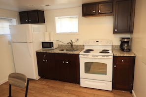 A kitchen with a refrigerator, microwave, stove, oven, and dark wooden cabinets.