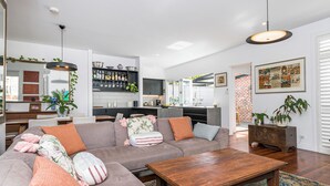 Ett modernt vardagsrum med en soffa, ett soffbord och ett köksområde i bakgrunden.