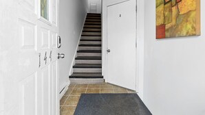 Un pasillo con una escalera, una puerta con el número 2 y un cuadro en la pared.