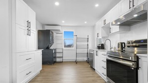 Una cocina moderna con armarios blancos, un horno de acero inoxidable y un ventanal con vistas.