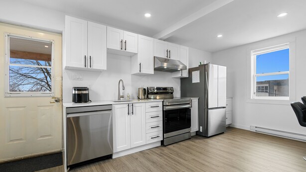 Una cocina moderna con armarios blancos, electrodomésticos de acero inoxidable y un ventanal grande.