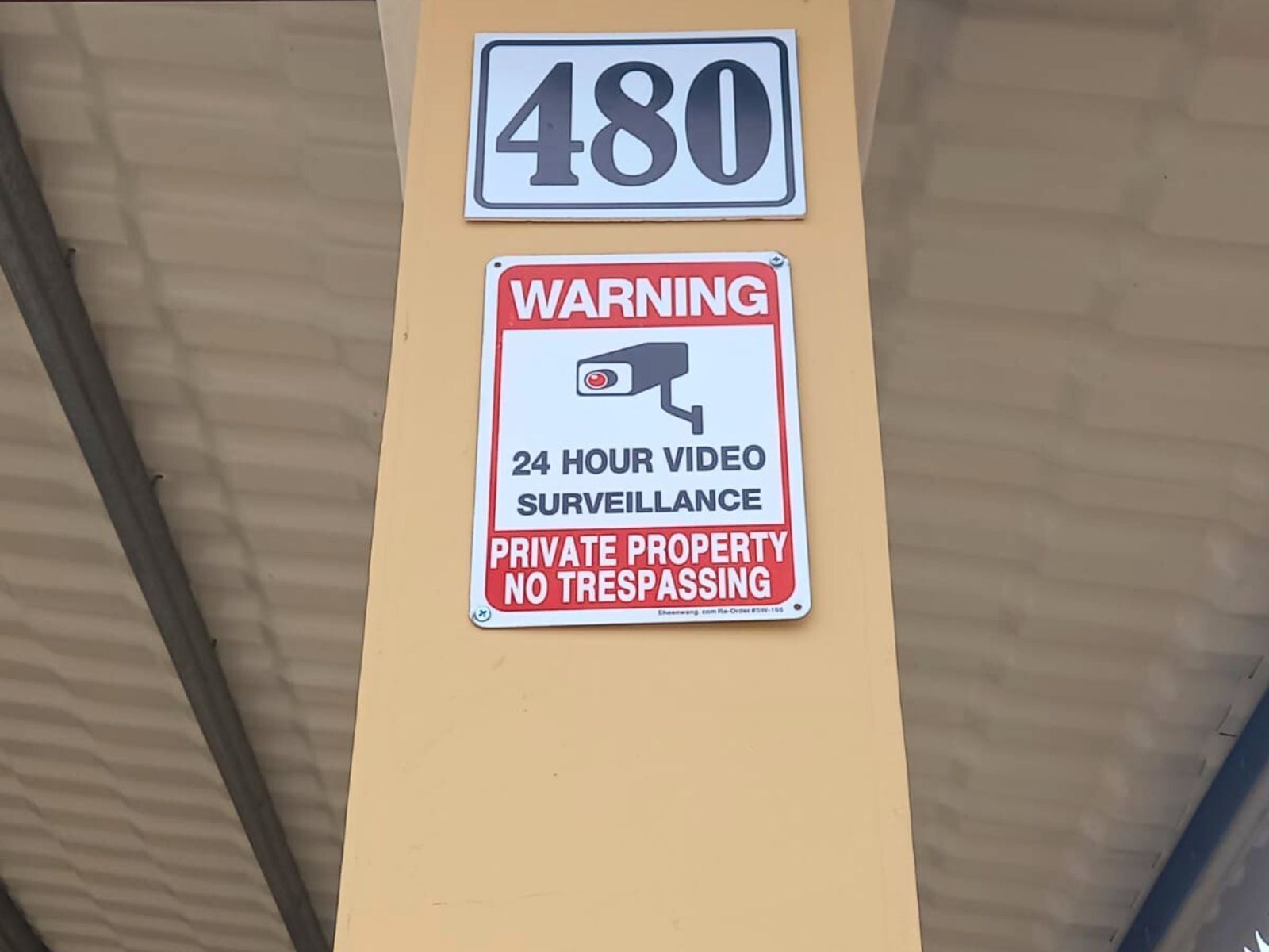 A building with a sign indicating '480' and a warning sign for '24 hour video surveillance' and 'no trespassing.'