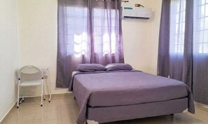 Une chambre à coucher avec un lit, une chaise et une fenêtre avec des rideaux.