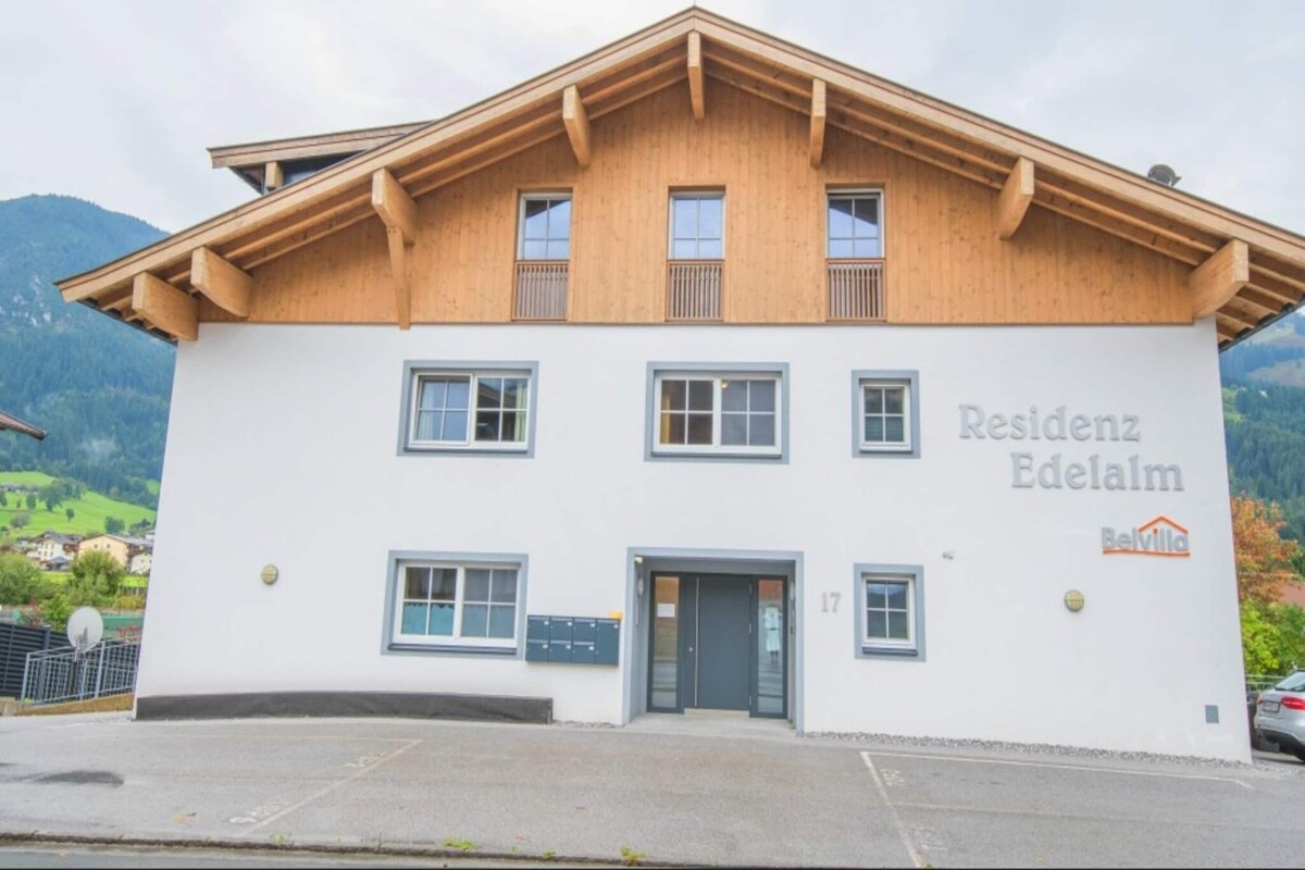 A two-story building with a wooden facade and a sign reading "Residenz Edelalm."