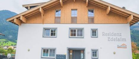 Un bâtiment à deux étages, doté d’une façade en bois et d’une enseigne indiquant « Residenz Edelalm ».