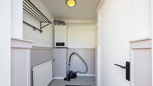 A narrow hallway with a radiator, a vacuum cleaner, and a door with a handle. - Holiday Home in De Koog Near Beach (De Koog)