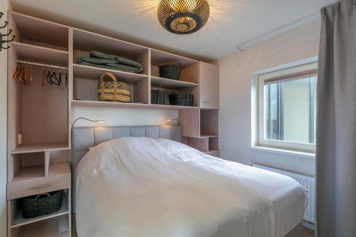 Ein Schlafzimmer mit Bett, Kleiderschrank, Fenster und Deckenleuchte.
