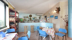 Un restaurante con zona de bar, sillas azules y una variedad de botellas en estanterías.