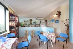 A restaurant with a bar area, blue chairs, and a variety of bottles on shelves. - Mediterranean Holiday Home for 4 (Ricadi)