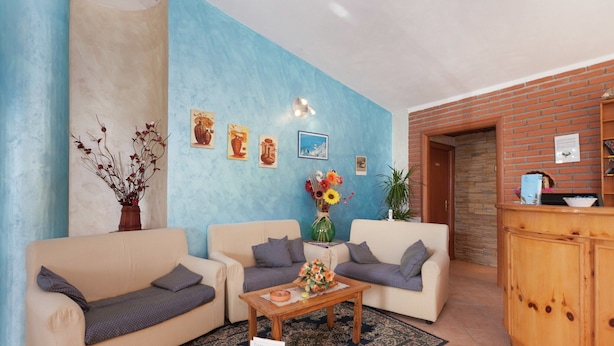 Una sala de estar con dos sofás color beige, una mesa de centro de madera y una pared azul de acento.