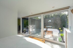 A modern room with a large sliding glass door leading to an outdoor patio with a table and chairs. - Bungalow in Sint Maartenszee With Garden Views (Sint Maartensvlotbrug)