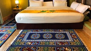 Ein Hotelzimmer mit einem großen Bett, einem Nachttisch mit Lampe und einem farbenfrohen Teppich.