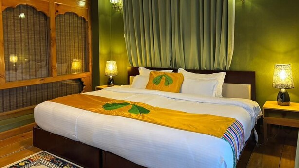 Ein Hotelzimmer mit einem großen Bett, zwei Nachttischlampen, einem Vorhang und einer dekorativen Wandverkleidung.