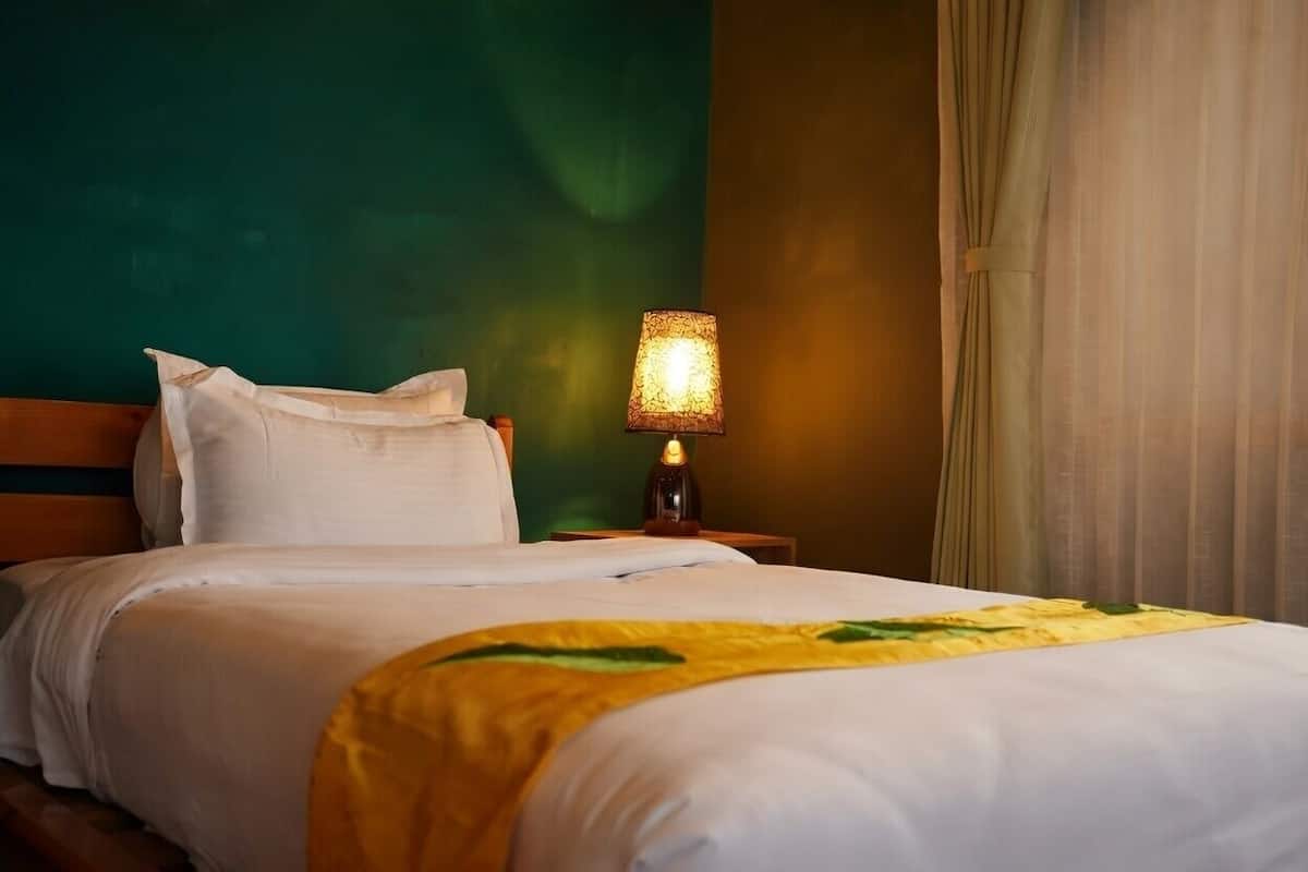 Una habitación de hotel con una cama, una lámpara y una cortina.