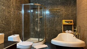 Ein Badezimmer mit einer Duschkabine, einer freistehenden Badewanne, einer Toilette und einem Handtuchhalter.
