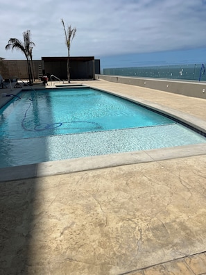 Une piscine rectangulaire Ă lâeau dâun bleu limpide, entourĂ©e dâune terrasse carrelĂ©e.