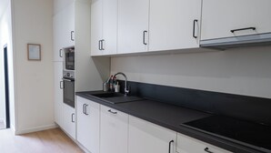Una cucina moderna con mobili bianchi, un piano di lavoro nero e una cappa in acciaio inossidabile.