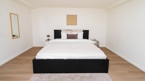 Una camera da letto con un letto, un comodino, una lampada, uno specchio e un quadro appeso al muro.