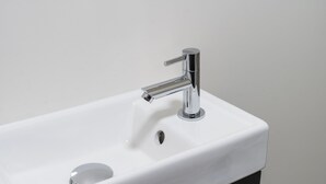 Un lavandino da bagno moderno con rubinetteria cromata e un solo foro di scarico.