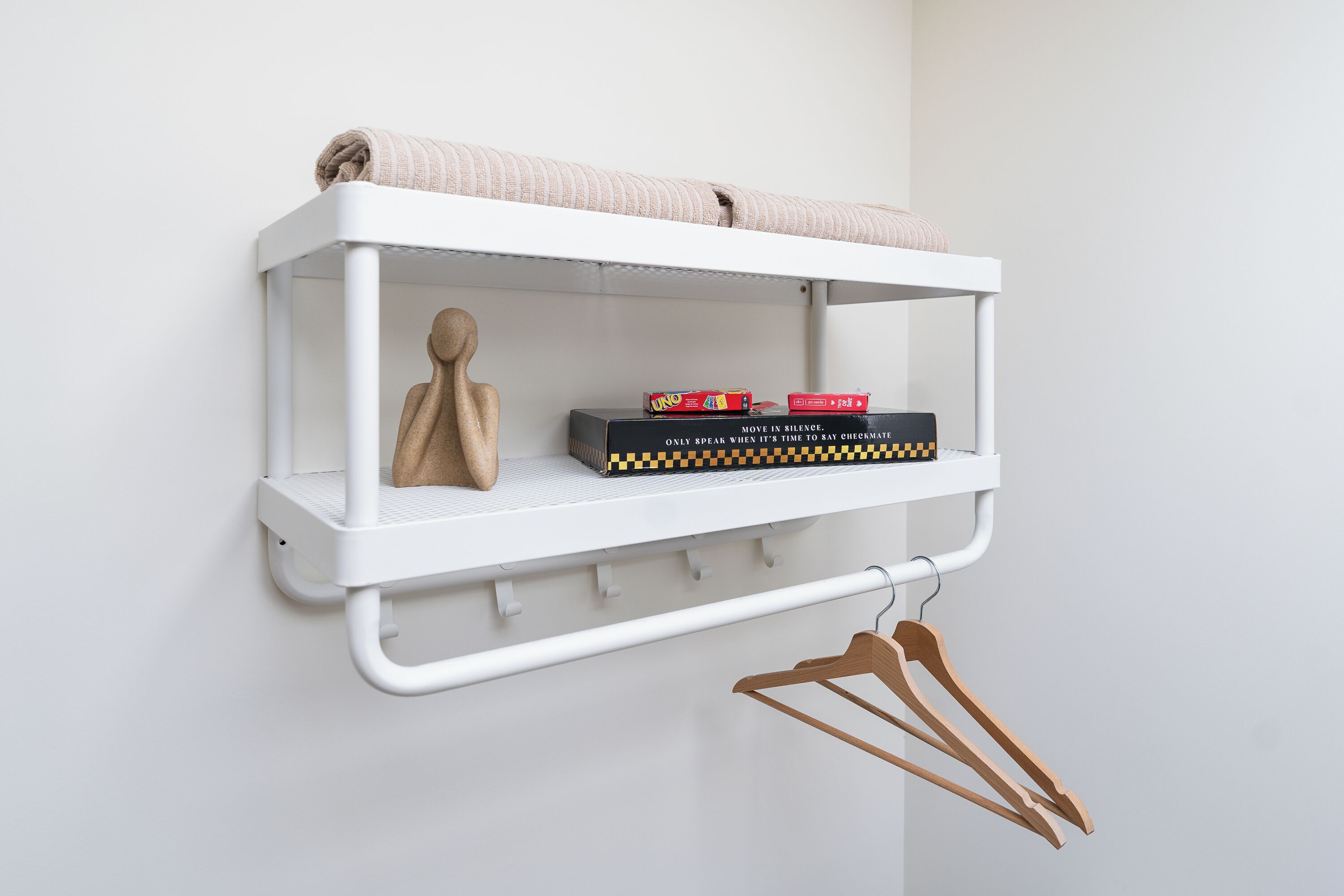 A white shelf with a towel, two books, and wooden hangers.