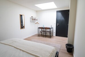 A bedroom with a bed, a desk, a chair, a hanging shelf, a door, and a skylight. - Relaxing 2 Private Rooms Close to Center (Ghent)