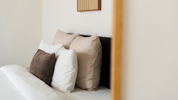 A bed with a white comforter and several pillows, a wooden headboard, and a wall-mounted artwork. - Cozy 3 Private Rooms Near to City Center (Ghent)