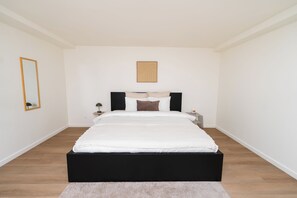A bedroom with a bed, a nightstand, a lamp, a mirror, and a wall art piece. - Cozy 3 Private Rooms Near to City Center (Ghent)