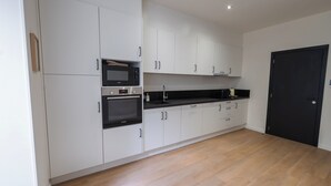 A modern kitchen with white cabinets, a black countertop, and a black door. - Cozy 3 Private Rooms Near to City Center (Ghent)