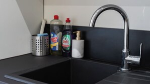 A kitchen sink with a chrome faucet, a stainless steel colander, and three bottles of dish soap. - Cozy 3 Private Rooms Near to City Center (Ghent)