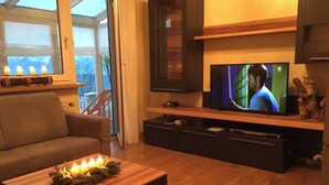 Un salon avec un téléviseur, un canapé et une table basse décorée de bougies.