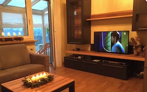 A living room with a TV, sofa, and a coffee table with candles.