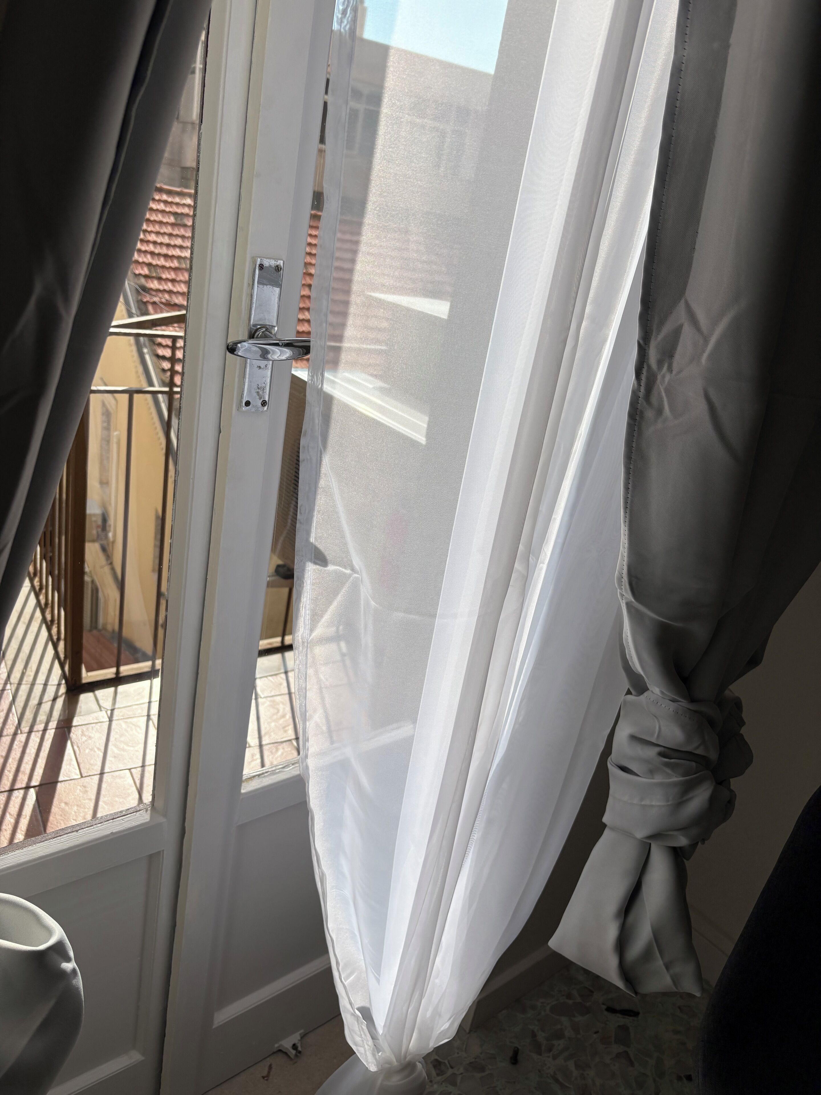 A room with a sliding glass door, a view of a balcony with a railing, and a tiled floor.
