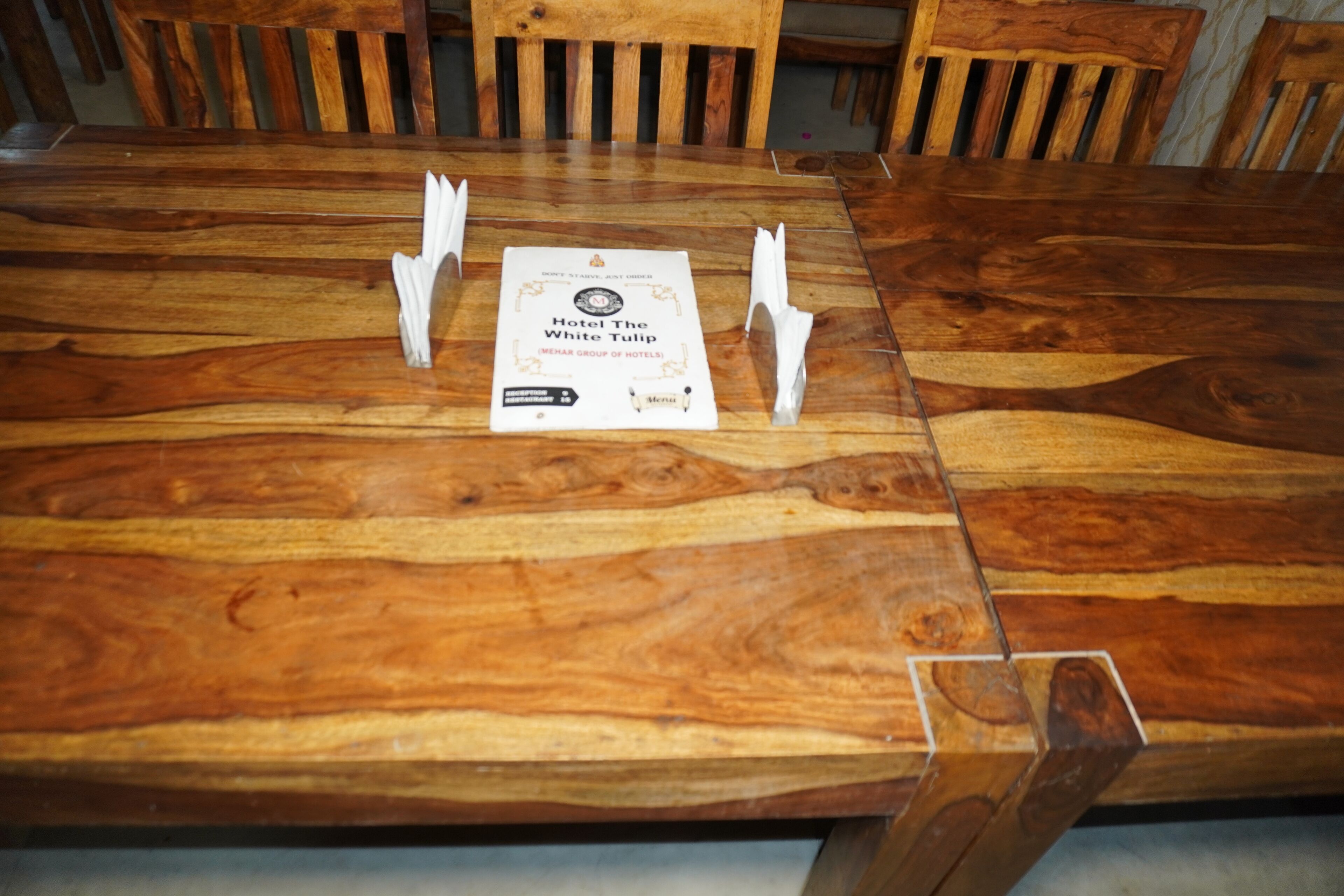 Een houten tafel met een menukaart en een certificaat van Hotel The White Tulip.