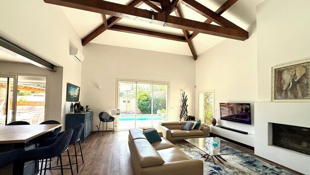 A spacious living room with a high ceiling, a sofa, a TV, and a fireplace. - Spacious, bright, fully renovated villa in an excellent location. (Istres)
