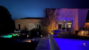 A pool area with a hot tub, a wooden deck, and a house with a tiled roof. - Spacious, bright, fully renovated villa in an excellent location. (Istres)