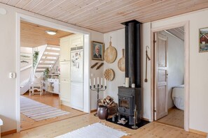 A cozy interior with a wooden floor, a black wood stove, and a staircase leading to another room. - Coastal Calmness in Stockevik Skärhamn (Skärhamn)