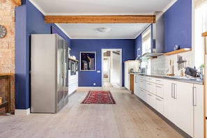 A modern kitchen with a refrigerator, cabinets, and a wooden beam ceiling. - Elegant 8BR Mansion Retreat (Delsbo)