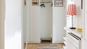 Ein schmaler Flur mit Holzboden, weißen Wänden und einer Tür zu einem Zimmer.