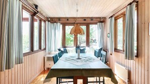 Una habitación con paneles de madera, una mesa de comedor, sillas y un colgante de luz.
