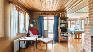 Una habitación acogedora con pisos de madera, una chimenea, una estantería y un comedor con mesa y sillas.