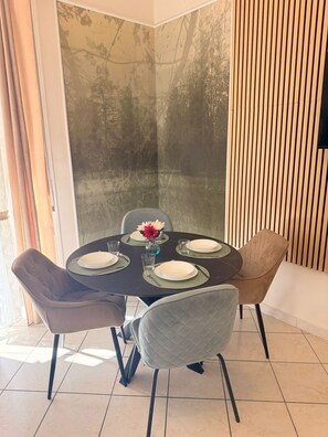 A dining area with a round table set for four, surrounded by cushioned chairs. - Tarantella House (Napoli)