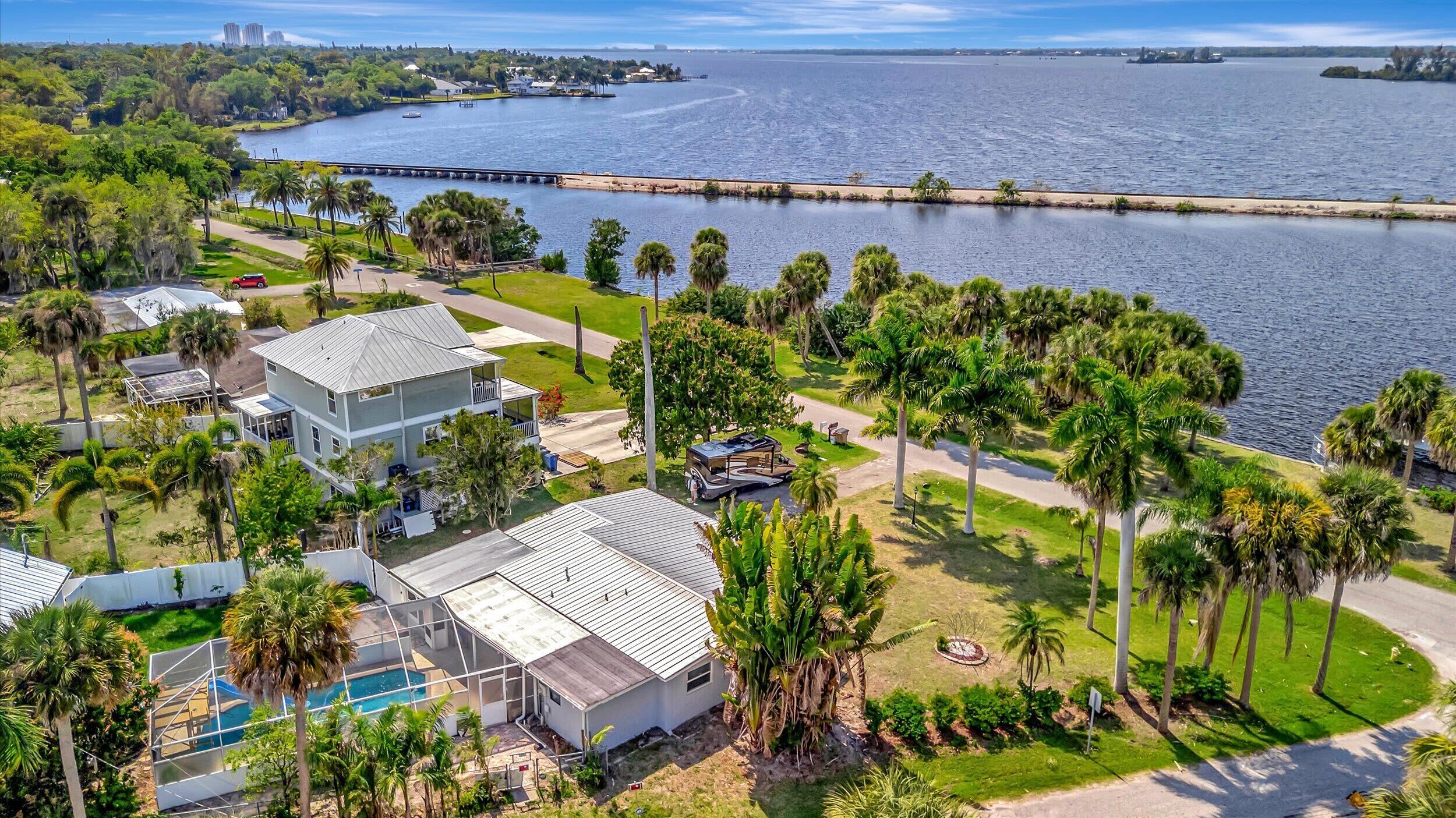 A residential area with a large house, a swimming pool, and a view of a body of water.