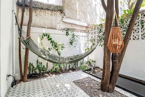 A hammock, a hanging lantern, and a tiled patio area with plants. - Private Oasis, Jacuzzi, Hammock, Water Feature (Ciudad de México)