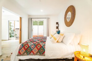 A bedroom with a bed, a mirror, a bedside lamp, and a view of the outdoors. - Private Oasis, Jacuzzi, Hammock, Water Feature (Ciudad de México)