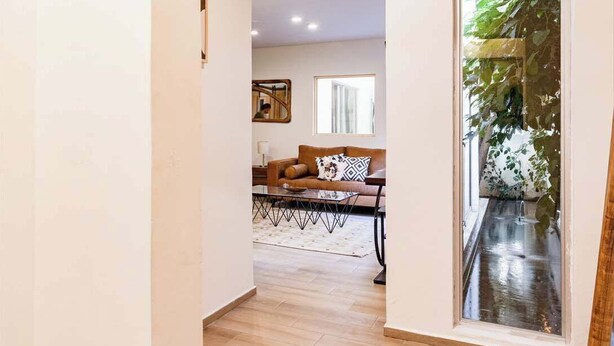 A hallway leading to a living room with a sofa, a coffee table, and a glass door with a plant. - Private Oasis, Jacuzzi, Hammock, Water Feature (Ciudad de México)