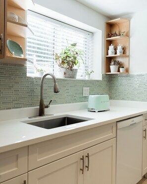 A modern kitchen with a sink, a toaster, and a potted plant.