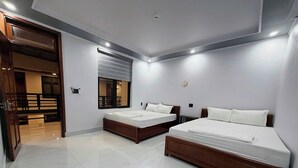 A modern bedroom with two beds, a large mirror, and a wooden door leading to a balcony. - Sunbeam Village Phong Nha (Phong Nha)