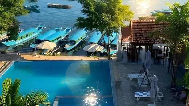 A pool area with lounge chairs and a small pavilion, surrounded by a river and hills. - Sunbeam Village Phong Nha (Phong Nha)