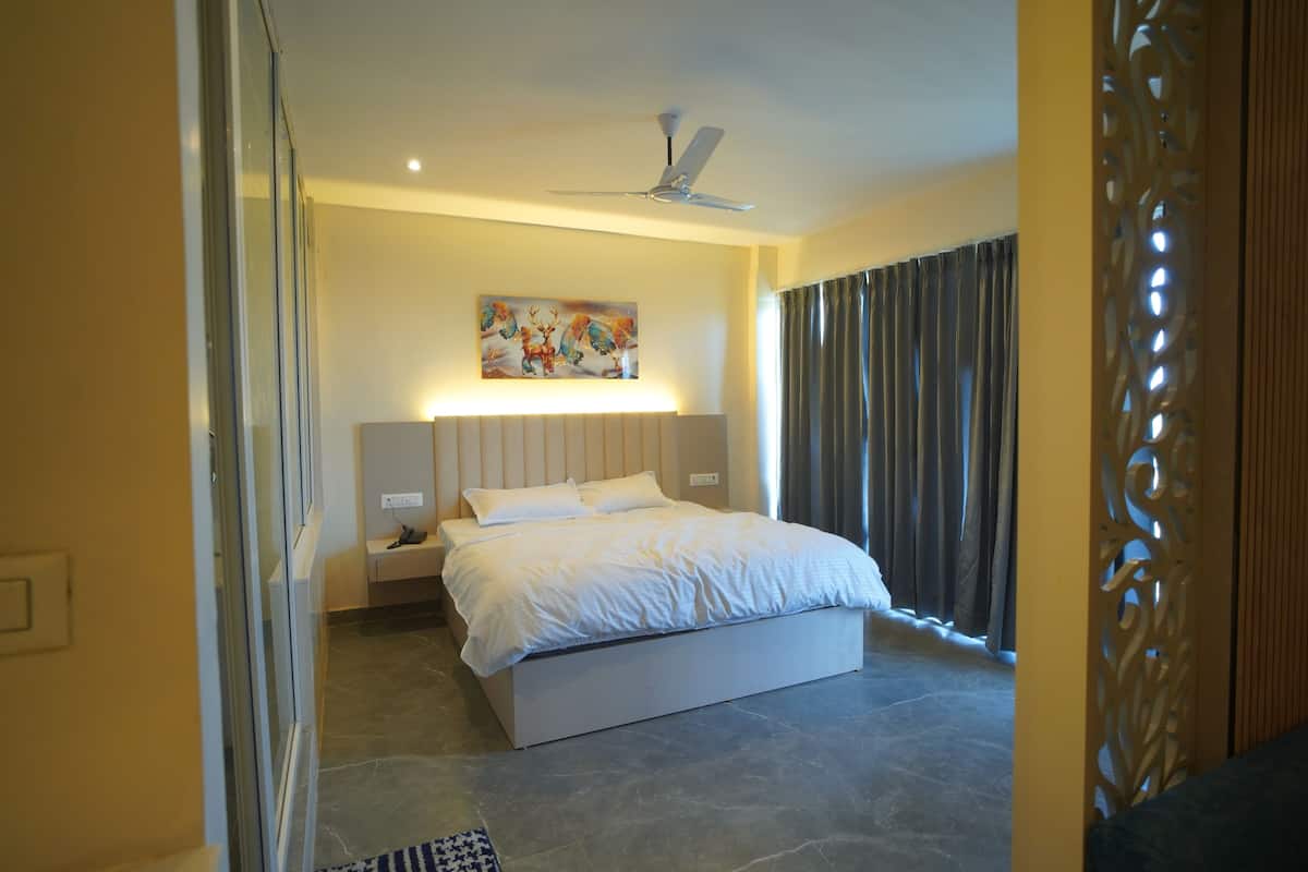 A bedroom with a bed, bedside tables, a ceiling fan, and a painting on the wall.